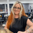 Kerry, Advanced Senior Stylist at Hair Pro UK in Bexhill-on-Sea, smiling warmly in front of the salon’s branded backdrop, representing decades of colour mastery, professional expertise, and long-standing dedication.