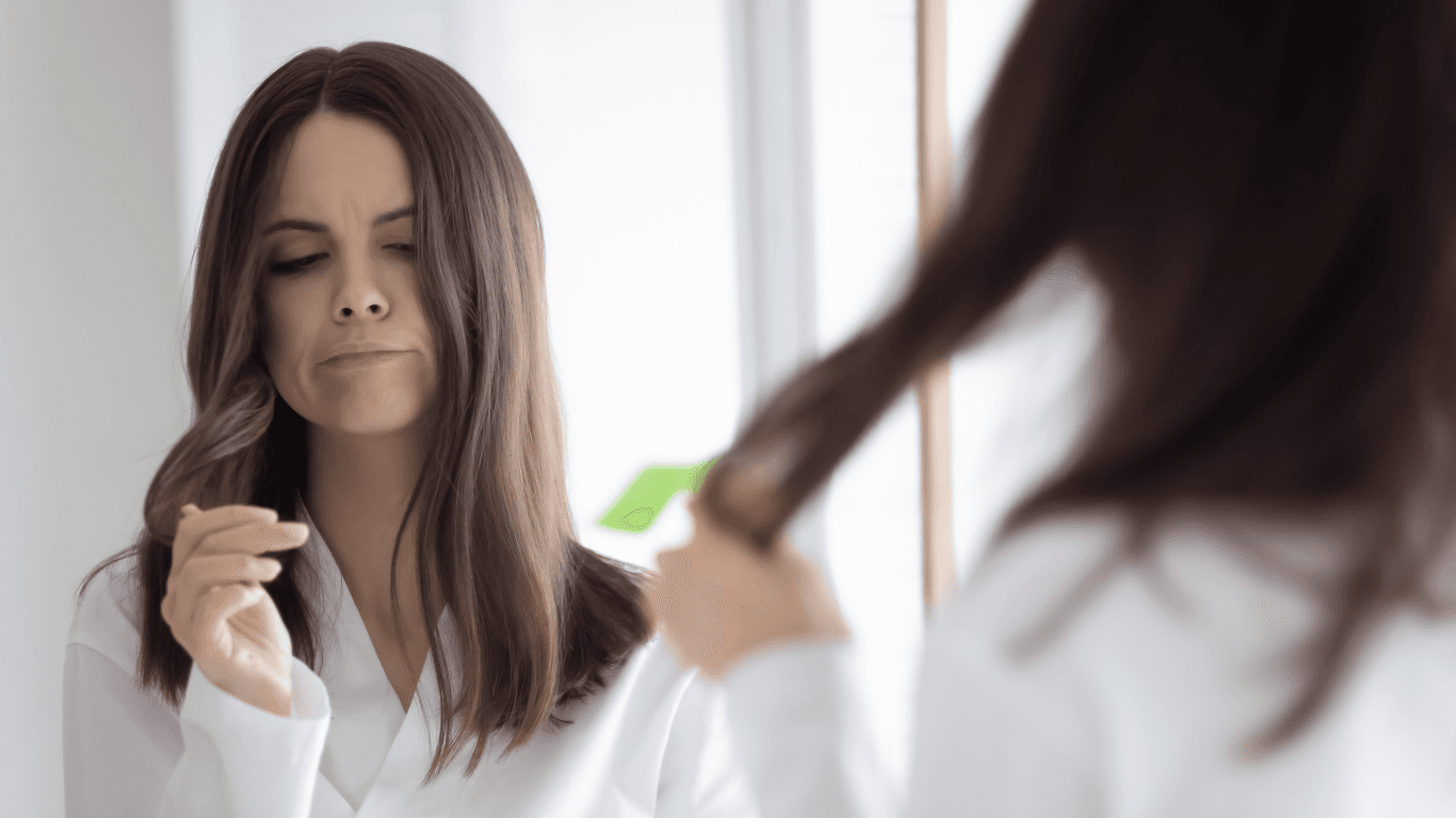 Woman examining split ends in front of a mirror, showing signs of dry, damaged hair — a common issue addressed by Hair Pro UK in Bexhill-on-Sea with expert care and professional Matrix products.